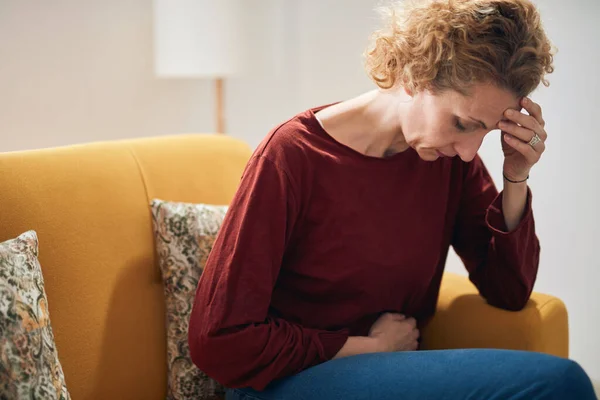 Frau Mit Bauchschmerzen Und Kopfschmerzen Sitzt Hause Auf Einer Couch — Stockfoto