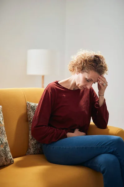 Frau Mit Bauchschmerzen Und Kopfschmerzen Sitzt Hause Auf Einer Couch — Stockfoto