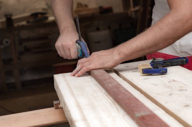 Erkek marangoz garajda ahşap malzemelerle çalışıyor..