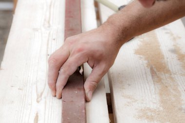 Erkek marangoz garajda ahşap malzemelerle çalışıyor..