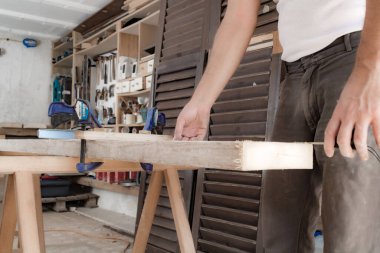 Erkek marangoz garajda ahşap malzemelerle çalışıyor..