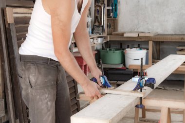 Erkek marangoz garajda ahşap malzemelerle çalışıyor..