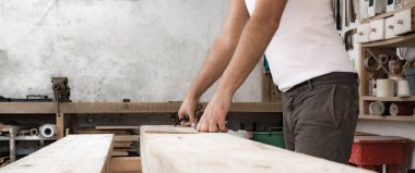 Erkek marangoz garajda ahşap malzemelerle çalışıyor..