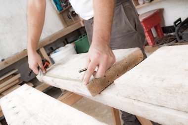 Erkek marangoz garajda ahşap malzemelerle çalışıyor..