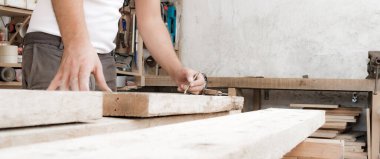 Erkek marangoz garajda ahşap malzemelerle çalışıyor..