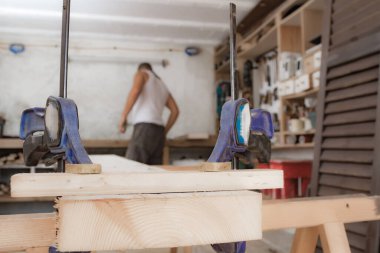 Erkek marangoz garajda ahşap malzemelerle çalışıyor..