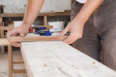 Erkek marangoz garajda ahşap malzemelerle çalışıyor..