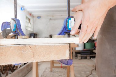 Erkek marangoz garajda ahşap malzemelerle çalışıyor..