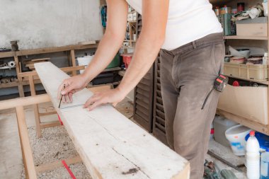 Erkek marangoz garajda ahşap malzemelerle çalışıyor..