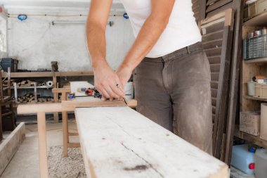 Erkek marangoz garajda ahşap malzemelerle çalışıyor..