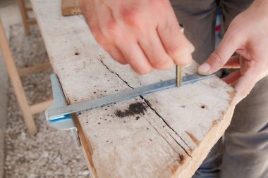 Erkek marangoz garajda ahşap malzemelerle çalışıyor..