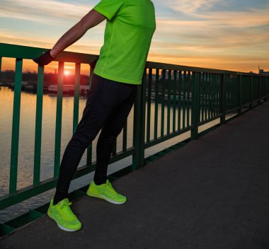 Nehrin yukarısındaki köprüde egzersiz yapan sportif bir adam..