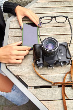 Modern akıllı telefon ve antika film kamerası kullanan bir kadın..