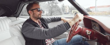 Antika elbiseli bir adam klasik Amerikan arabası kullanıyor..