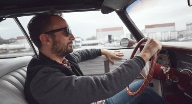 Antika elbiseli bir adam klasik Amerikan arabası kullanıyor..