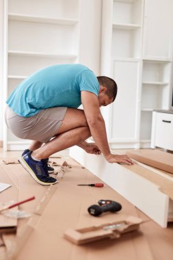 Tamirci yeni dairede mobilya montajı yapıyor, taşınıyor ve çok çalışıyor..