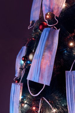 Cerrahi maskelerle süslenmiş Noel ağacı - virüs salgını 2020 / 2021 sosyal mesafesi, tecrit ve karantina izolasyonu.