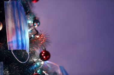 Cerrahi maskelerle süslenmiş Noel ağacı - virüs salgını 2020 / 2021 sosyal mesafesi, tecrit ve karantina izolasyonu.