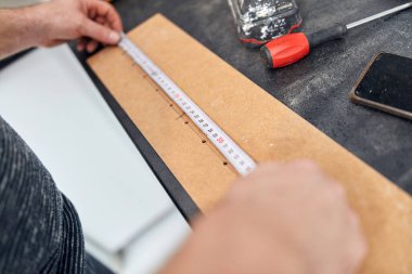 Tamirci ev eşyaları tamir ederken mezura kullanıyor..