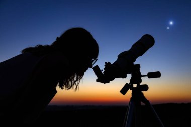 Woman looking at night sky with amateur astronomical telescope. clipart