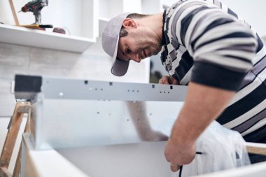 Tamirci işçi ev mobilyalarını tamir edip monte ediyor..