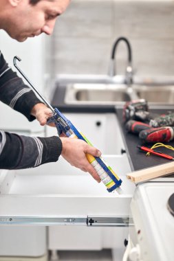 Tamirci ev eşyaları için silikon dolgu macunu yapıştırıcısı kullanıyor..