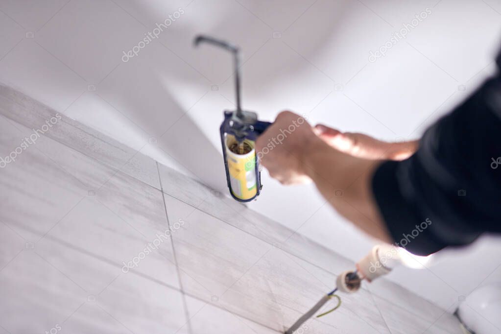 Handyman using silicone sealant adhesive bond for fixing household things.