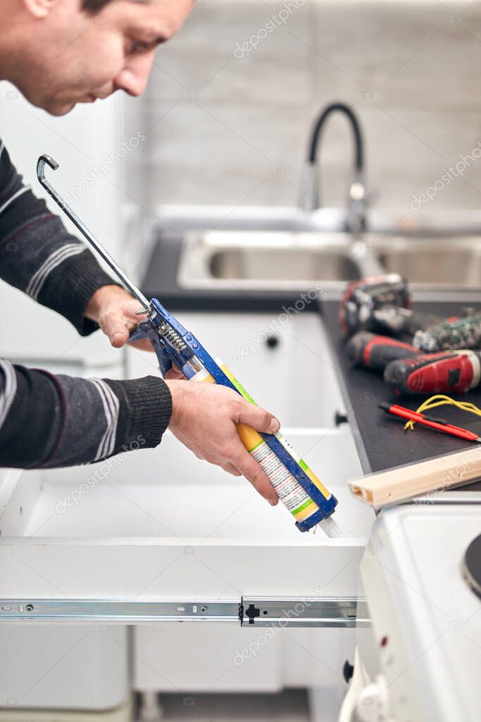 Handyman using silicone sealant adhesive bond for fixing houshold things.