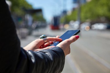 Avrupa 'da bir tramvay istasyonunda cep telefonu kullanan bir kadın..