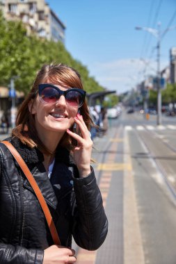 Avrupa 'da bir tramvay istasyonunda cep telefonu kullanan bir kadın..