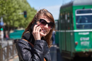 Avrupa 'da bir tramvay istasyonunda cep telefonu kullanan bir kadın..