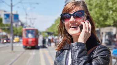 Avrupa 'da bir tramvay istasyonunda cep telefonu kullanan bir kadın..