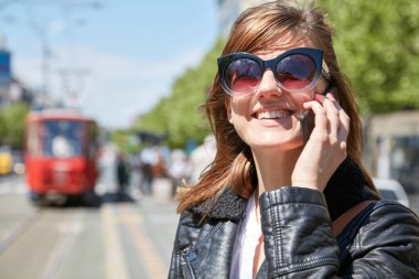 Avrupa 'da bir tramvay istasyonunda cep telefonu kullanan bir kadın..