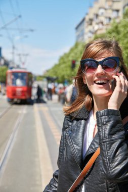 Avrupa 'da bir tramvay istasyonunda cep telefonu kullanan bir kadın..