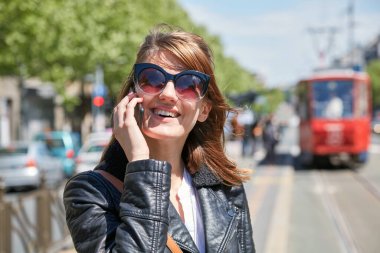 Avrupa 'da bir tramvay istasyonunda cep telefonu kullanan bir kadın..