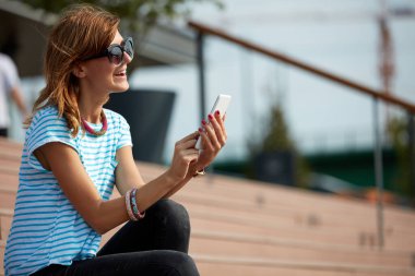 Genç bir kadın açık havada modern akıllı telefon kullanıyor..