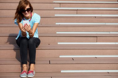 Genç bir kadın açık havada modern akıllı telefon kullanıyor..