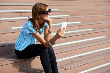 Genç bir kadın açık havada modern akıllı telefon kullanıyor..