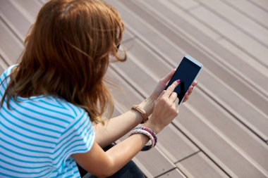 Genç bir kadın açık havada modern akıllı telefon kullanıyor..