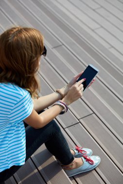 Genç bir kadın açık havada modern akıllı telefon kullanıyor..