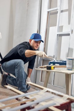 Genç yetişkin bir adam, yeni evinin DIY bütçe tadilatında resim yapıyor..