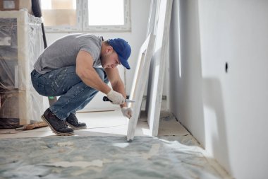 Genç yetişkin bir adam yeni evinin DIY bütçe tadilatı üzerinde çalışıyor..