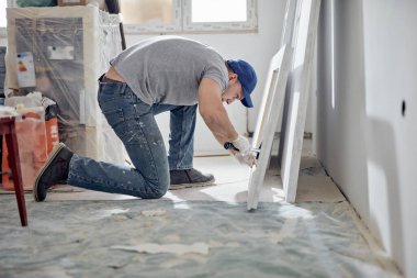 Genç yetişkin bir adam yeni evinin DIY bütçe tadilatı üzerinde çalışıyor..