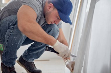 Genç yetişkin bir adam yeni evinin DIY bütçe tadilatı üzerinde çalışıyor..