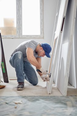 Genç yetişkin bir adam yeni evinin DIY bütçe tadilatı üzerinde çalışıyor..