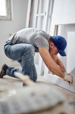 Genç yetişkin bir adam yeni evinin DIY bütçe tadilatı üzerinde çalışıyor..