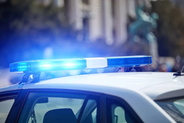 Police car with blue lights on the crime scene in traffic urban environment.