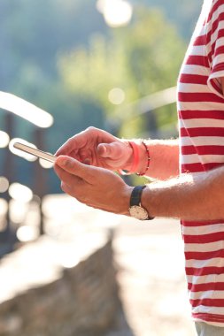 Parkta modern akıllı telefon kullanan genç bir adam..