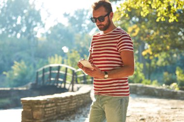 Parkta modern akıllı telefon kullanan genç bir adam..