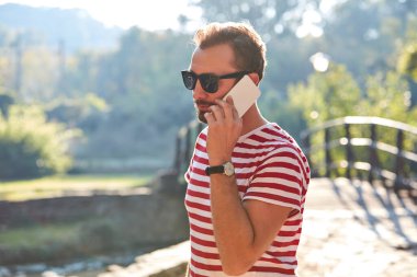 Parkta modern akıllı telefon kullanan genç bir adam..